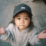 A young child holding their hands open in a gesture of curiosity and uncertainty, representing the natural process of asking questions and learning